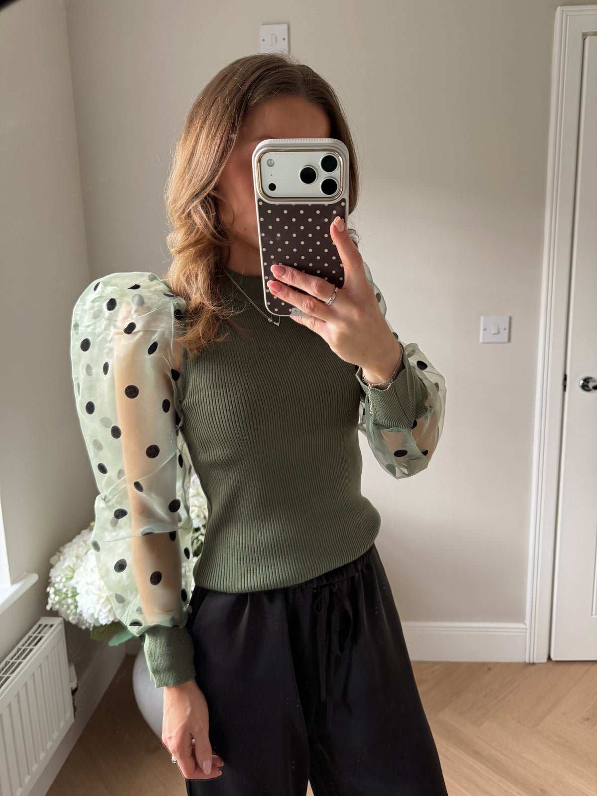 close up of khaki jumper with sheer polka dot sleeves.