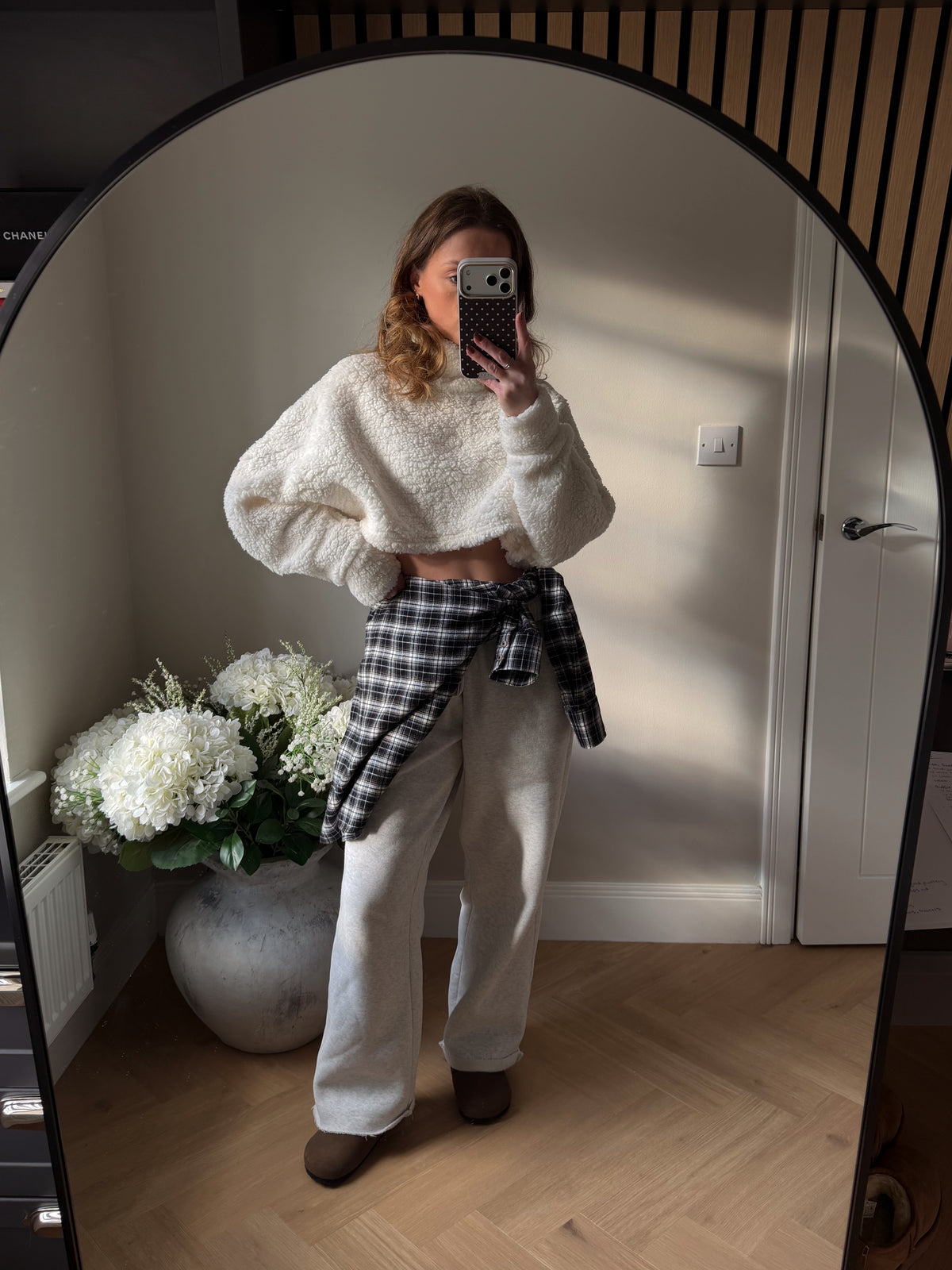 Cream high neck teddy style cropped batwing jumper. Worn with wide leg grey jogger and a checked shirt wrapped around waist.
