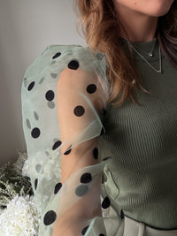 Close up of khaki sheer sleeves with black polka dots in a velvet material.