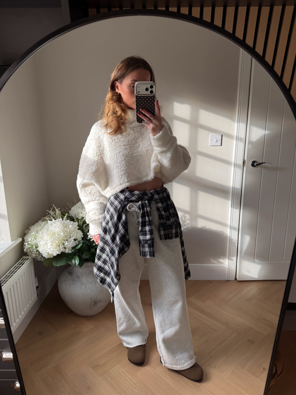 Cream soft fleecy cropped long sleeve jumper paired with grey joggers and shirt tied around the waist.