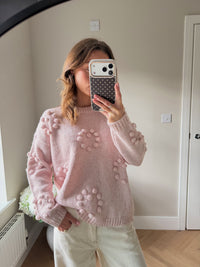 Pink chunky style jumper with pom poms shaped into the outline of hearts.